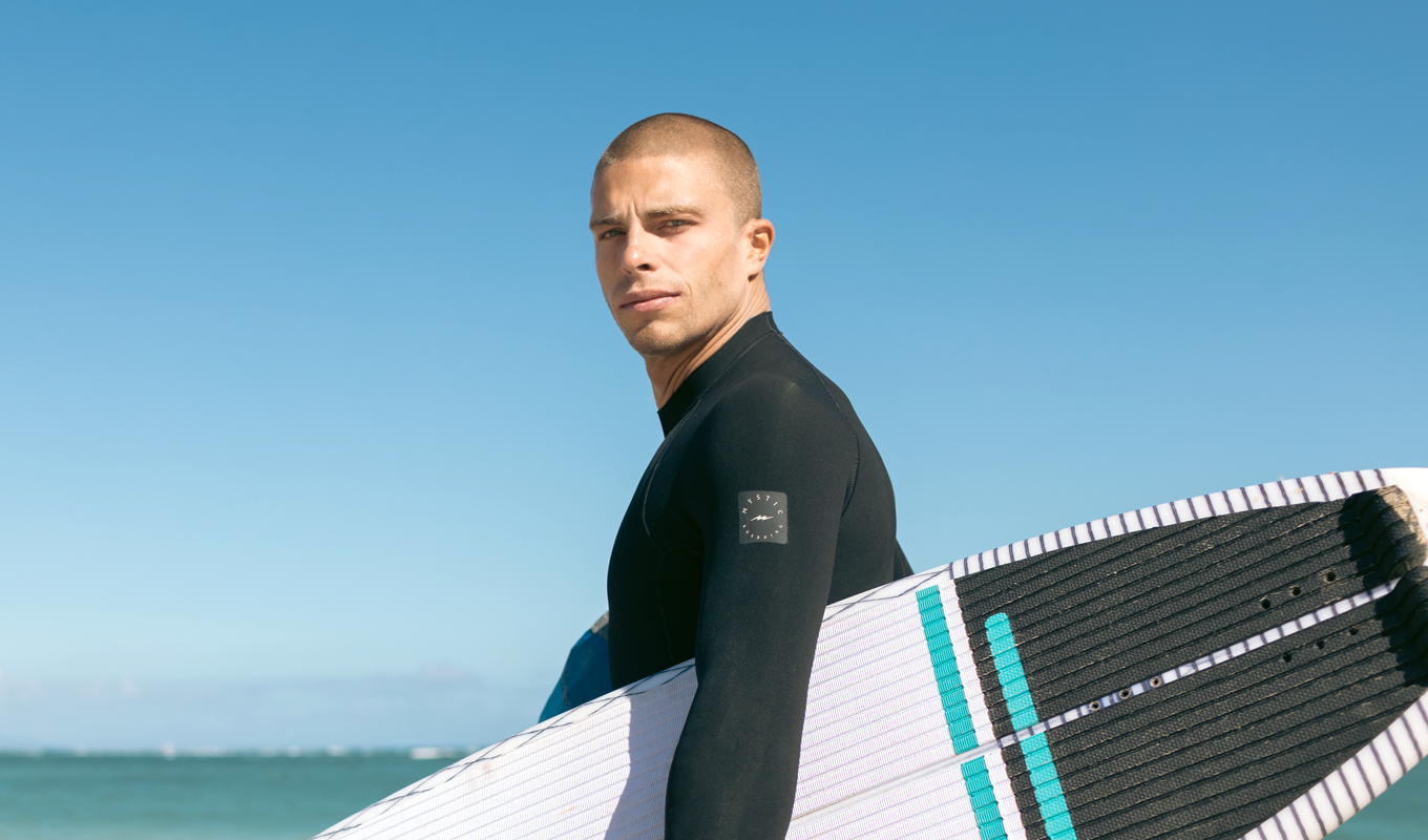 Camille Delannoy holding surfboard by the sea