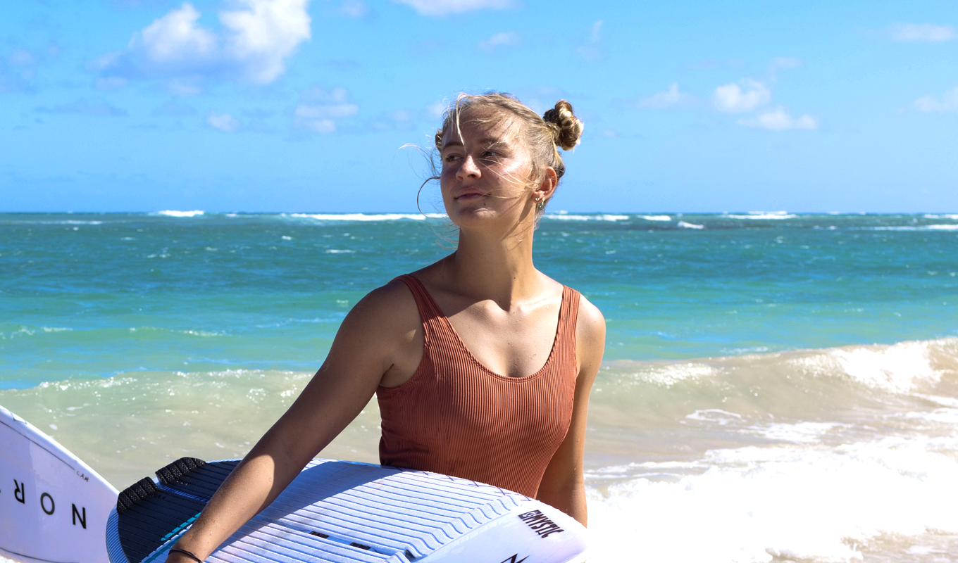 Capucine Delannoy holding surfboard by the sea